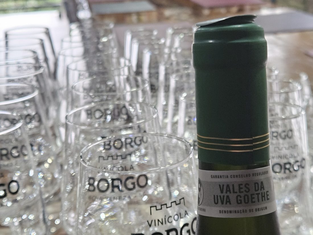 Garrafa da Vinícola Borgo com a Denominação de Origem Vales da Uva Goethe, entre as taças da casa
